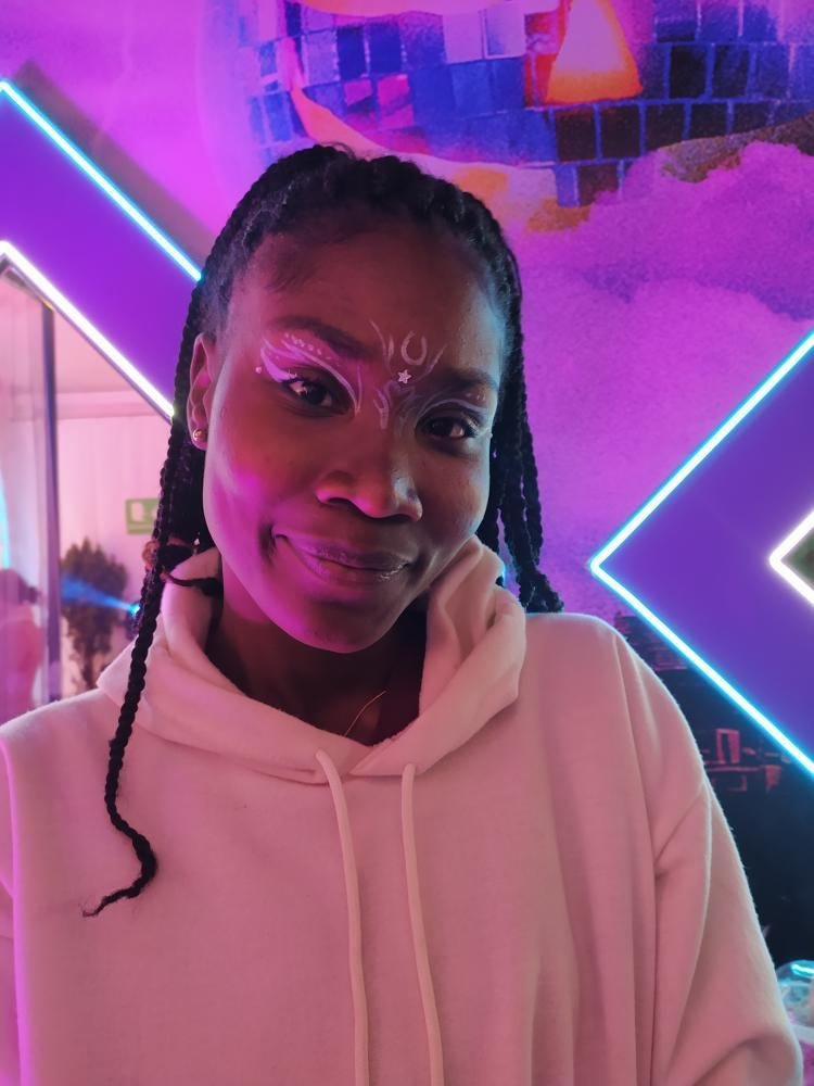 Asistente con maquillaje artístico luminoso en un evento nocturno