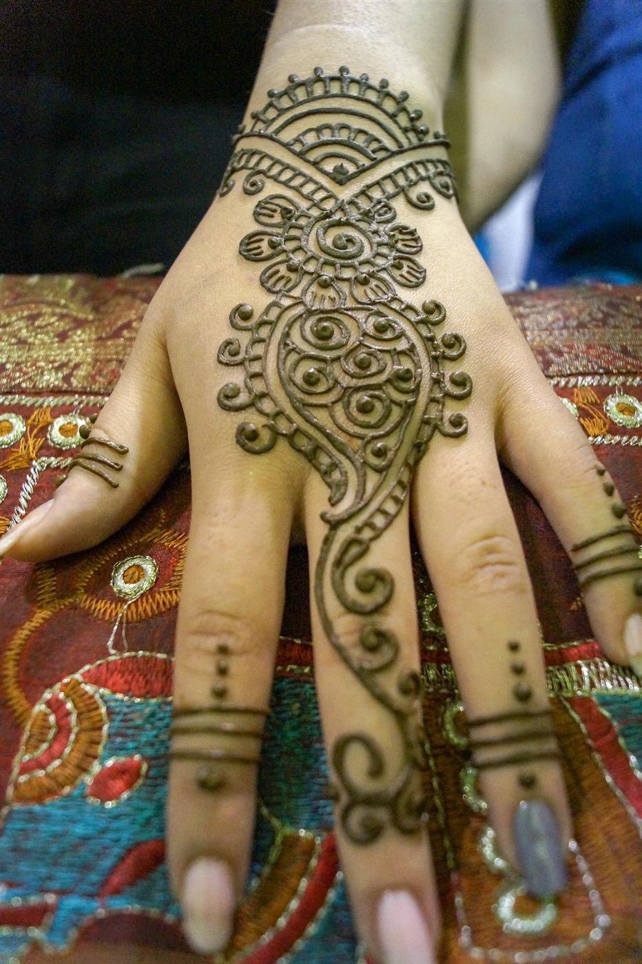 Diseño de mehendi en henna sobre la mano de una invitada