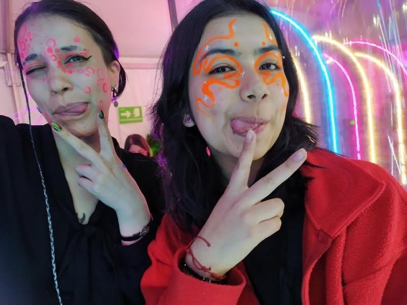Asistentes con maquillaje artístico de colores en un evento nocturno