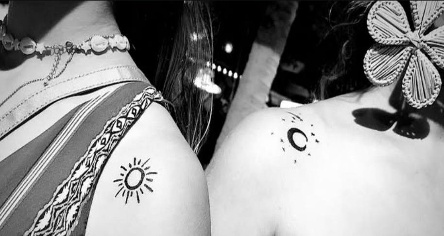 Tatuajes temporales pintados a mano con pincel sobre los hombros de dos asistentes
